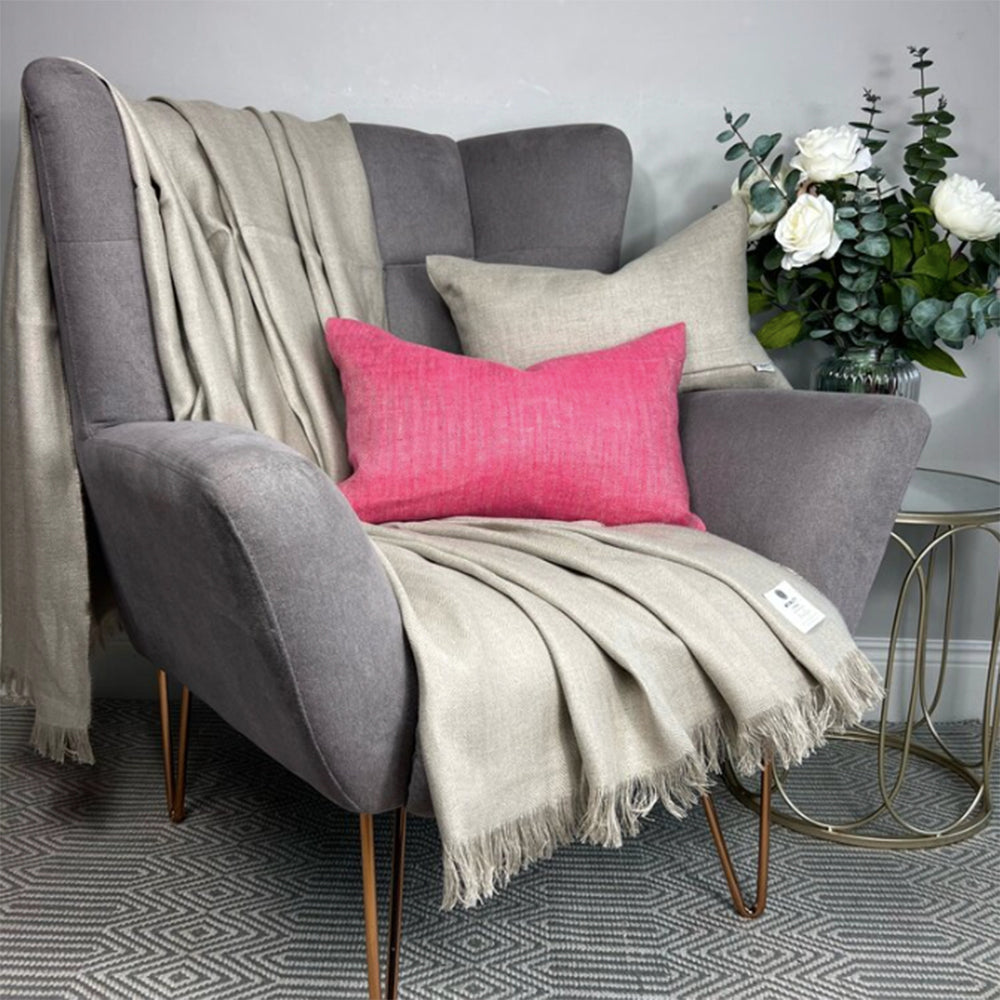 Oatmeal linen blanket on gray chair with pink pillow