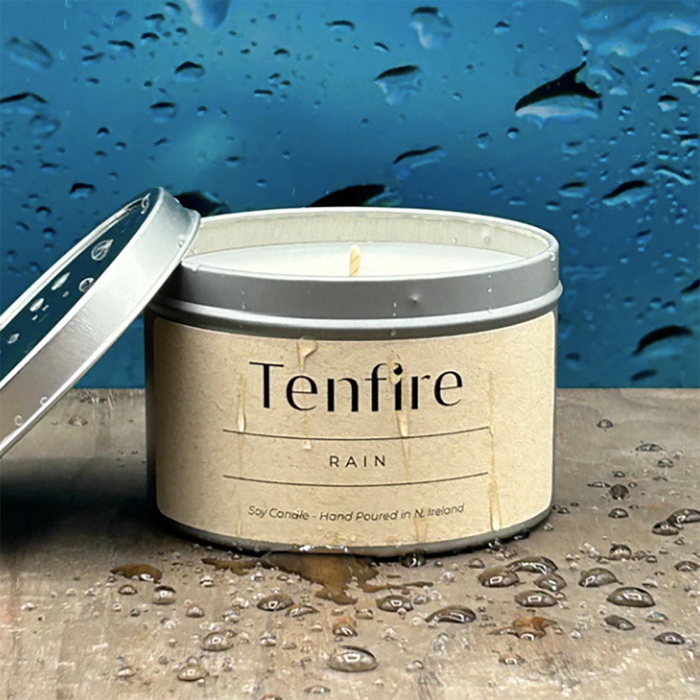 Candle in a tin labeled Tenfire Rain with lid open.