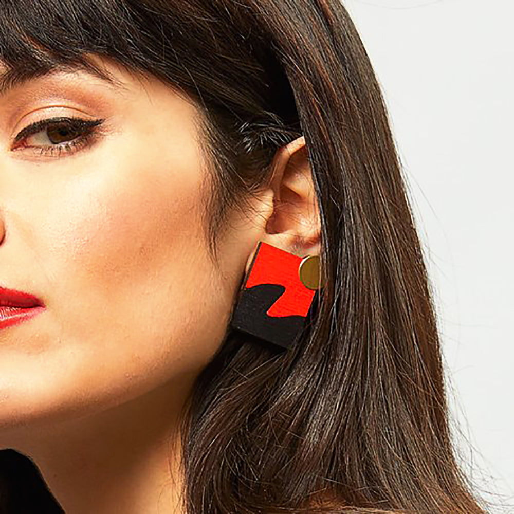 Woman wearing square, black and red wavy earrings
