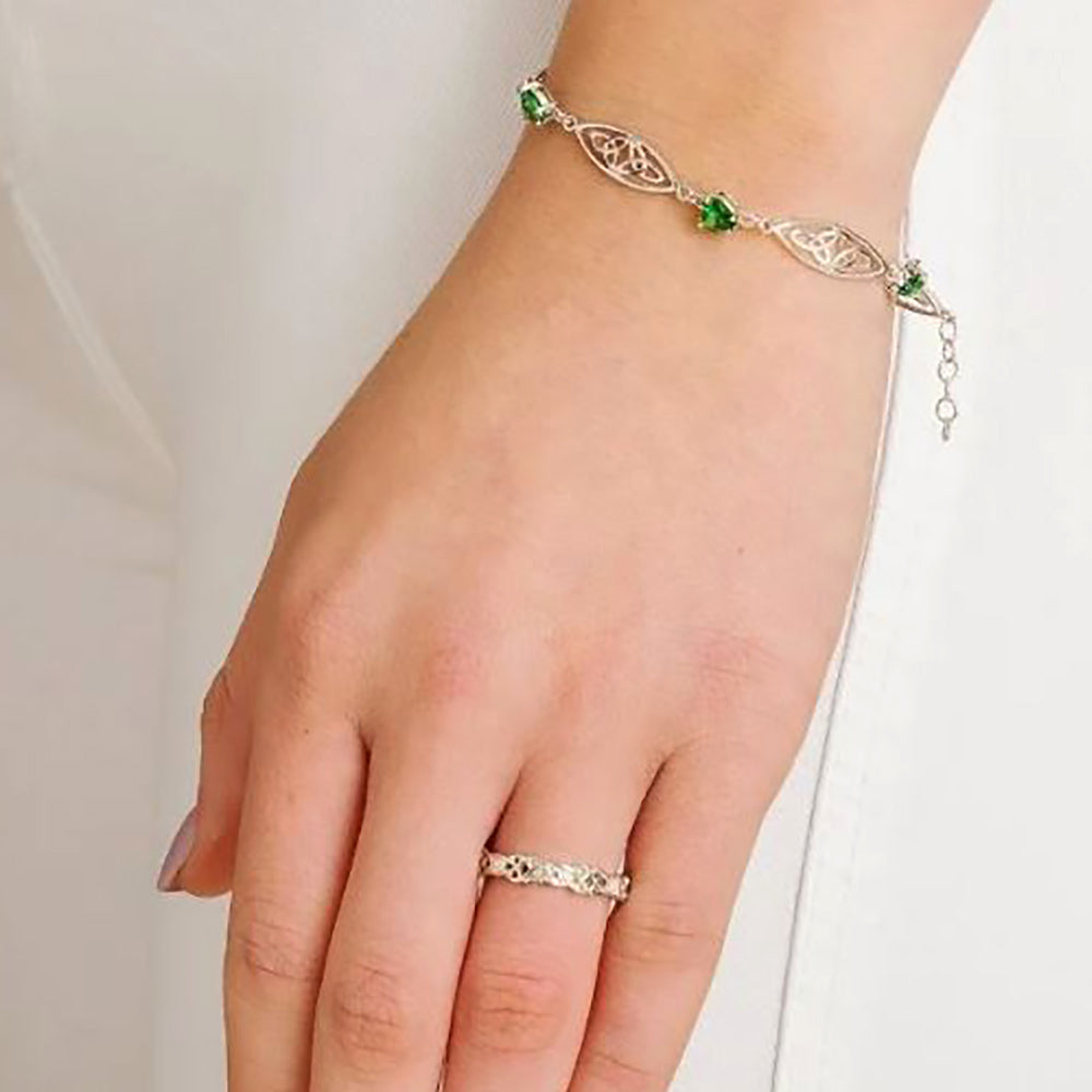 sterling silver trinity bracelet with emerald green stone hearts on a models wrist.
