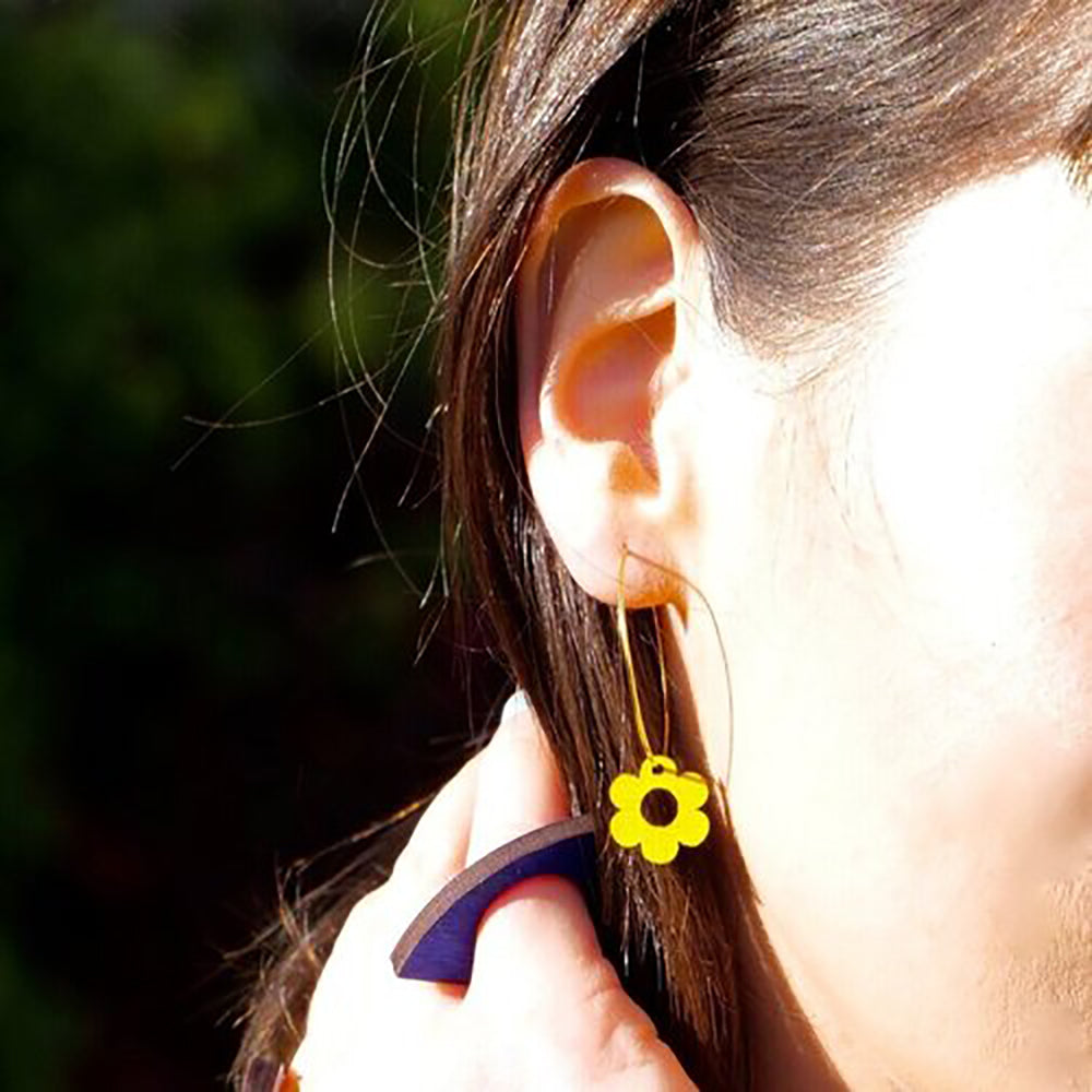 Woman wearing yellow wooden daisy earrings
