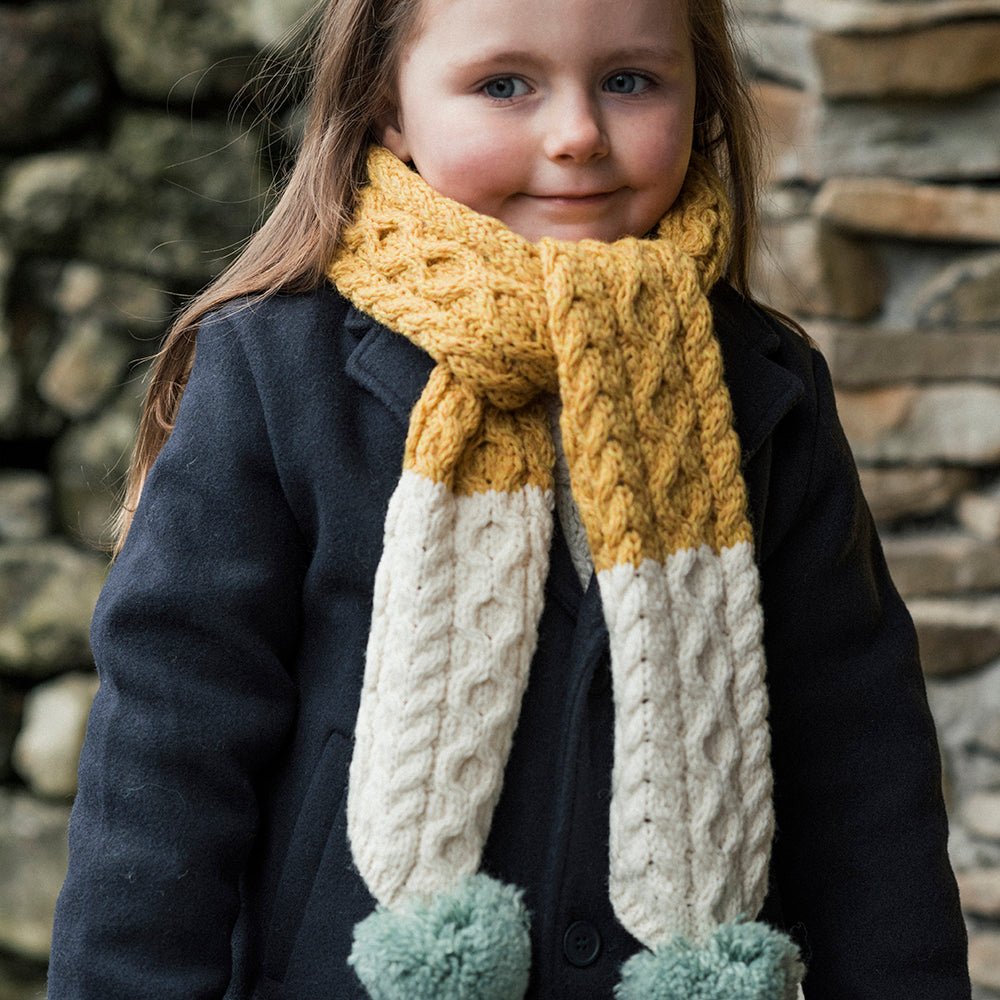 Kid wearing Aran Woollen Mills yellow, cream, and aqua scarf