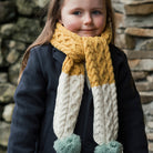Kid wearing Aran Woollen Mills yellow, cream, and aqua scarf