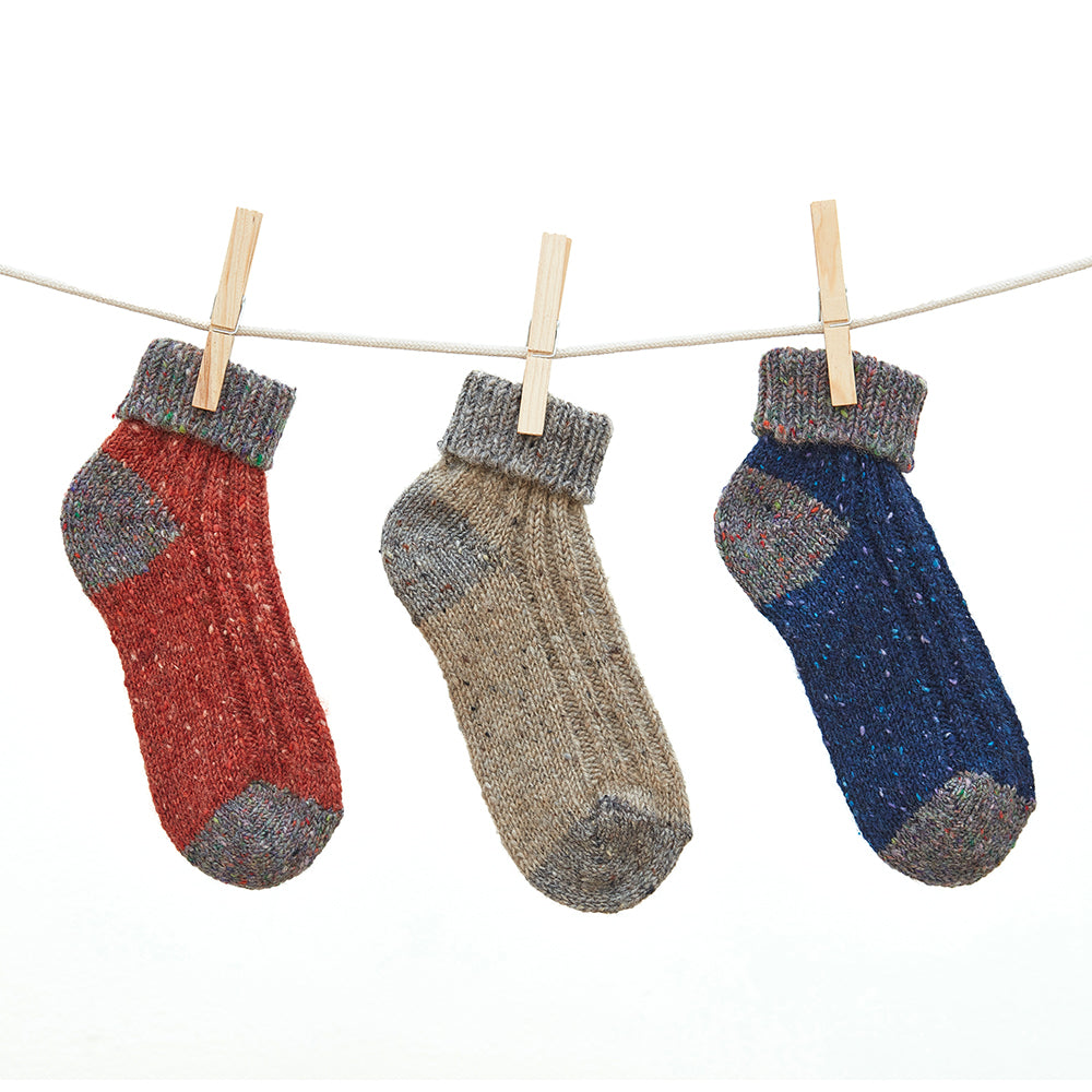 Aran wool ankle socks in Terracotta, Oatmeal, and Navy on a clothesline.