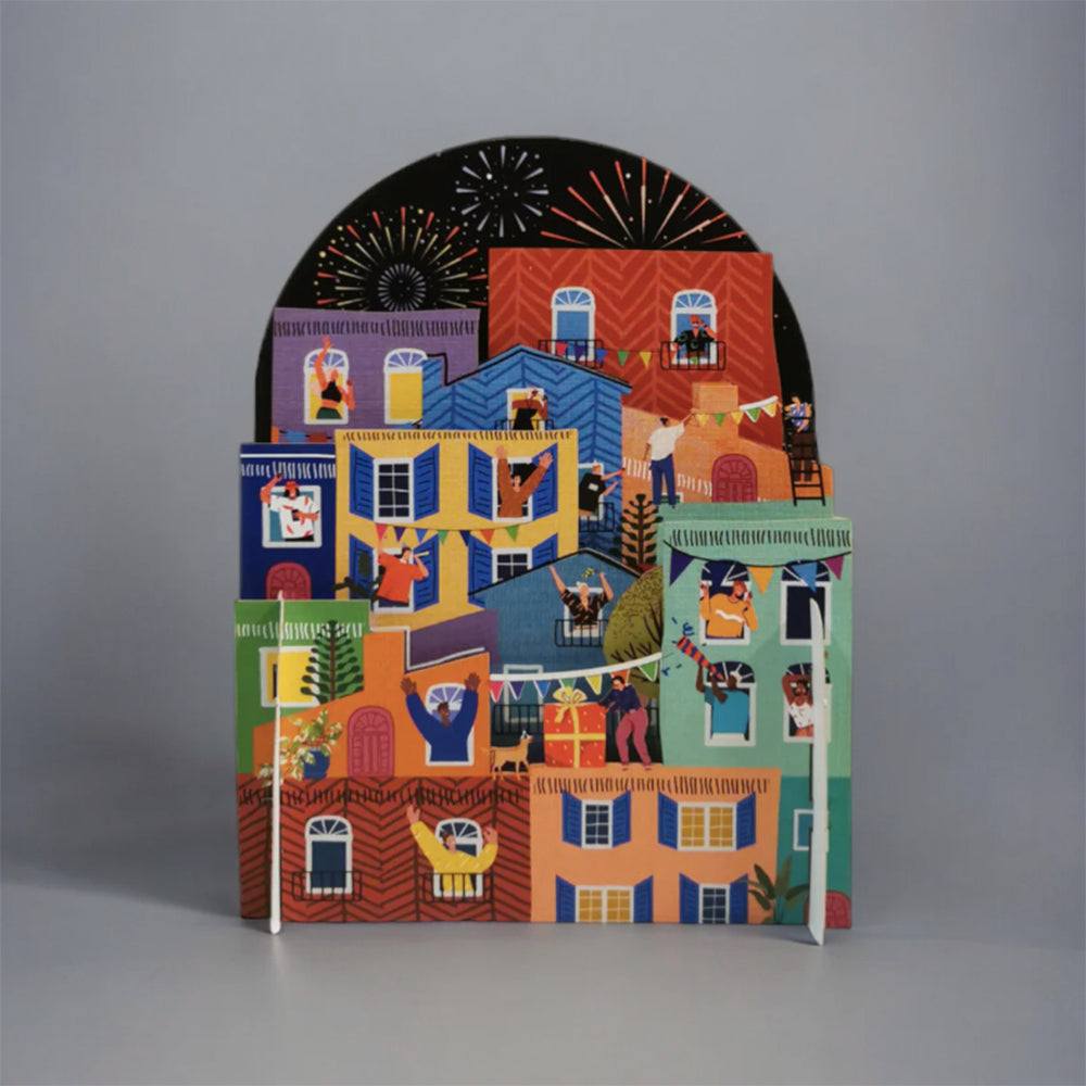 Pop-up cityscape with celebrating figures & fireworks.