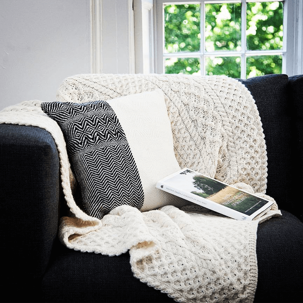 Aran blanket draped on couch with pillows and book