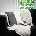 Aran blanket draped on couch with pillows and book