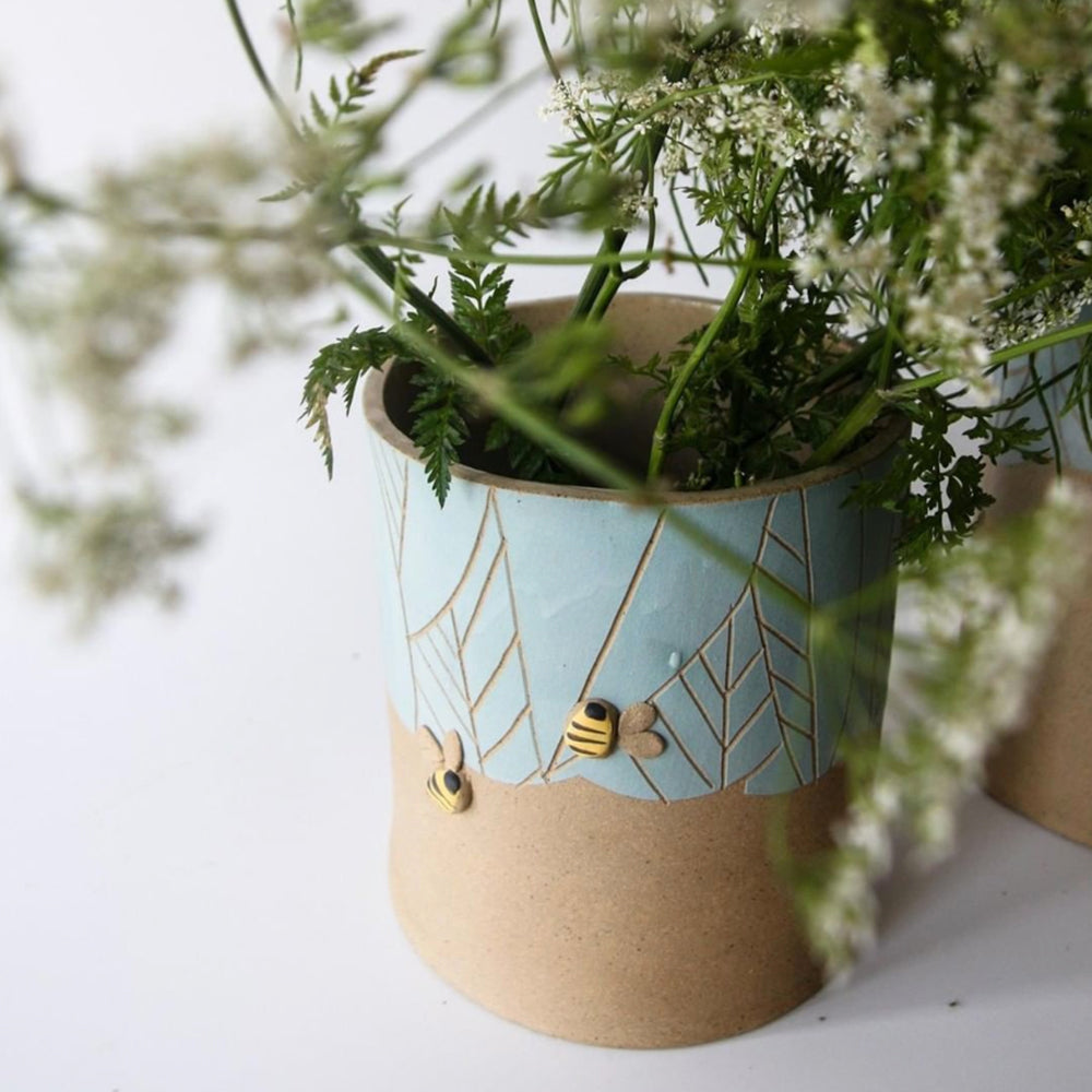 Bee flower pot with blue leaves and two bees.