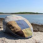 Patchwork tweed cap on a rock by the water