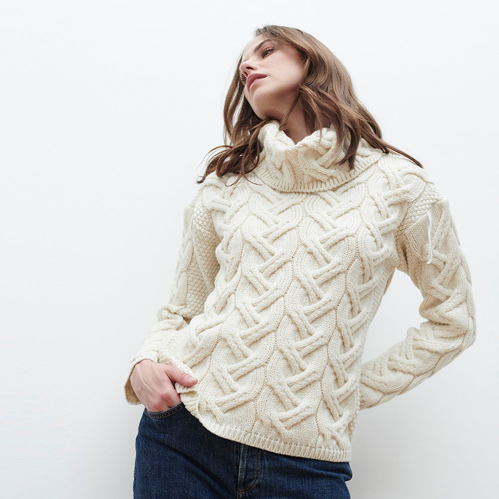Woman in cream chunky cable knit cowl neck sweater