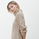Woman in beige cowl neck Aran sweater dress