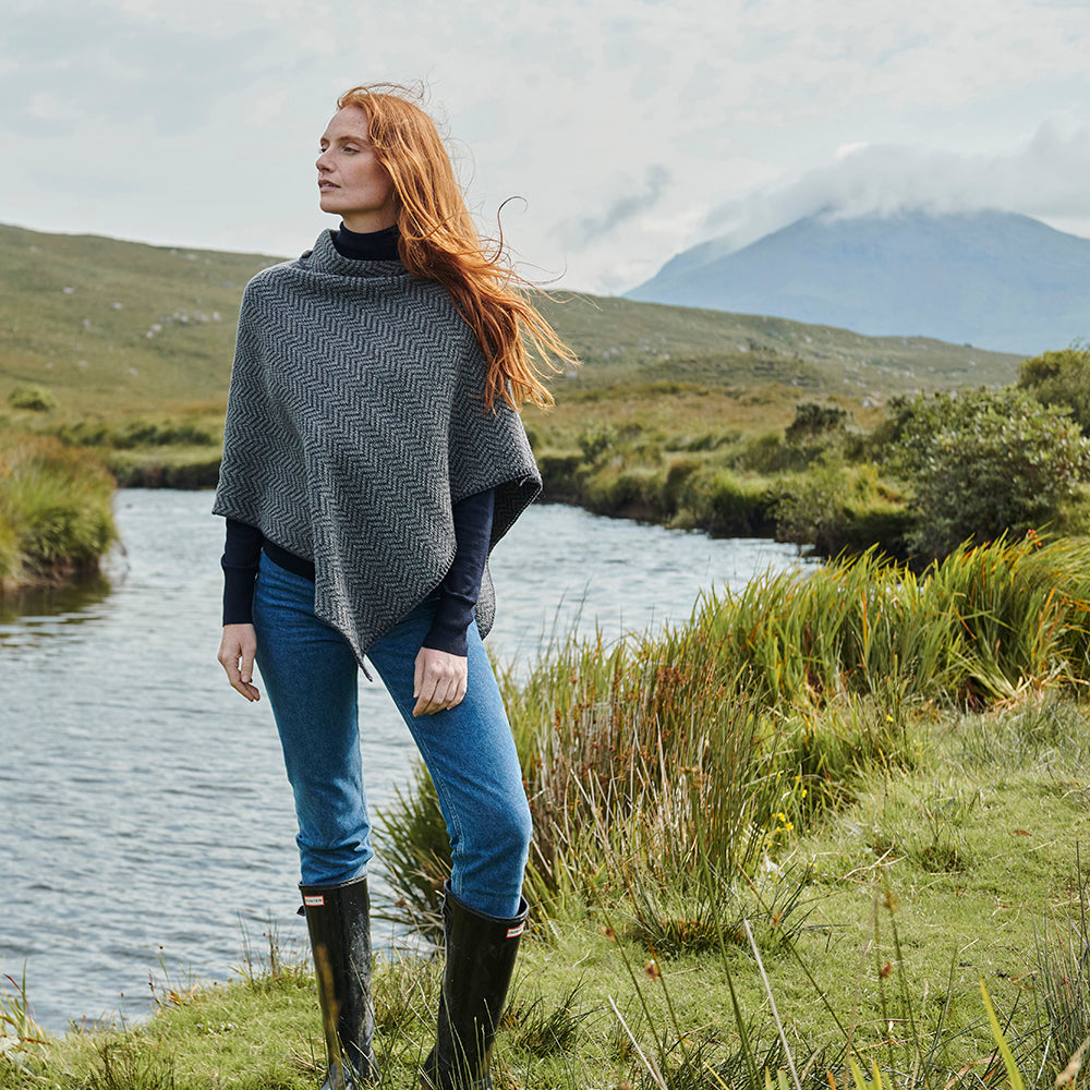 Woman wearing charcoal herringbone poncho with buttons