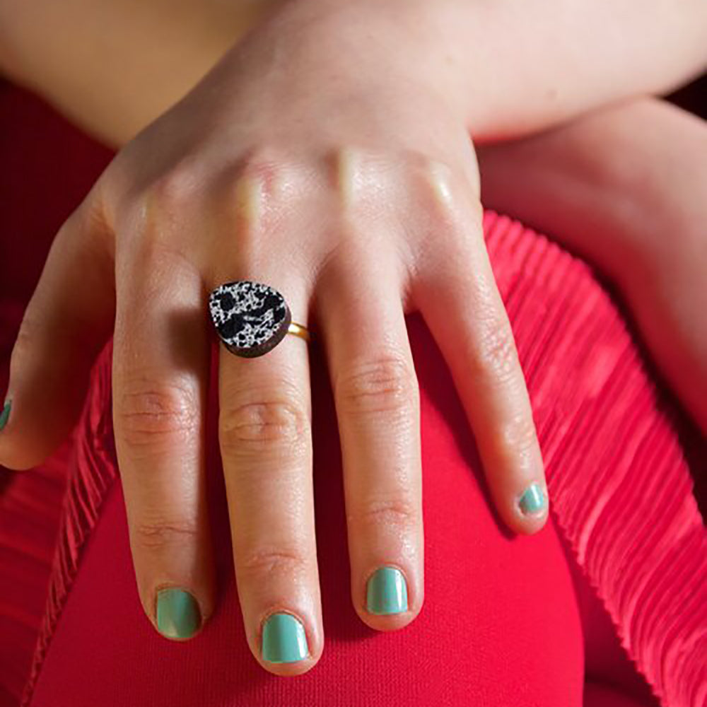 spattered black and white wooden egg ring on model hand 