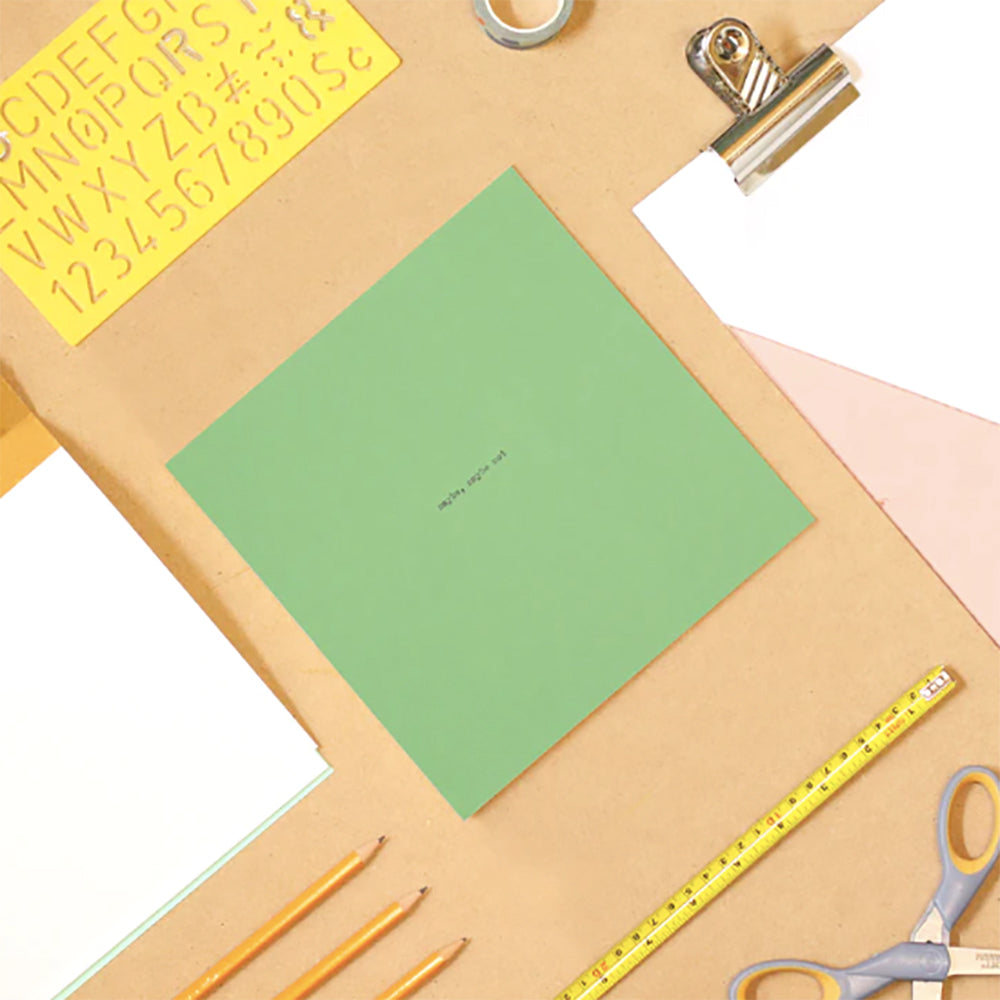 Green square notebook on desk with stationery