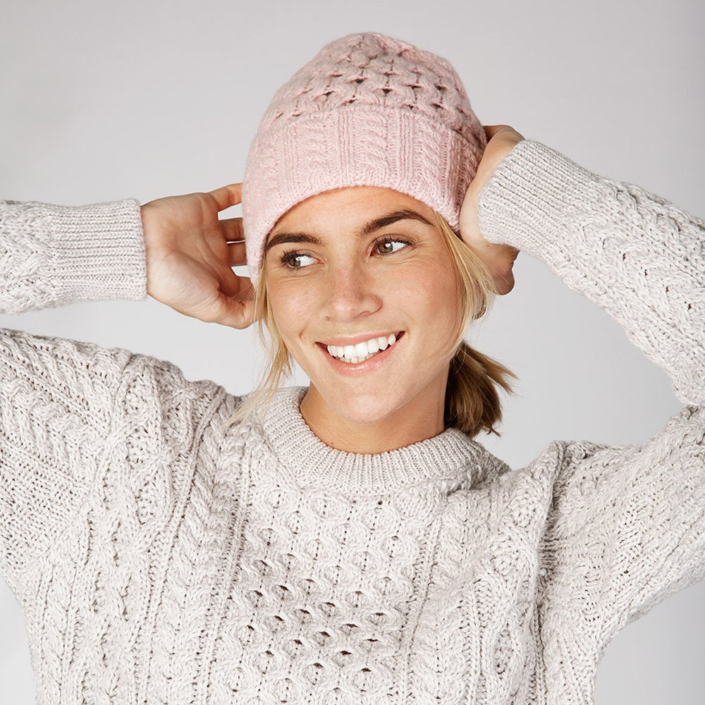 Woman wearing square pink mist beanie and sweater.