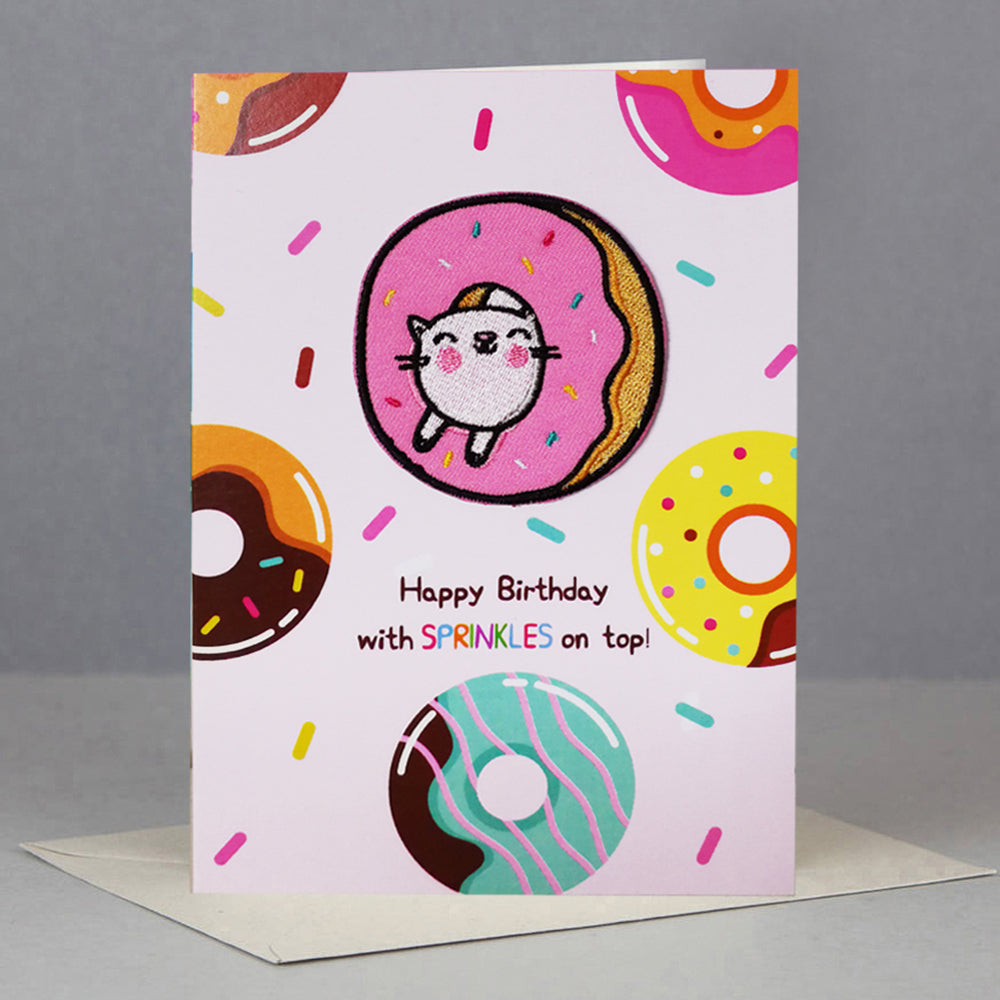Birthday card with cat in donut and colorful sprinkles.
