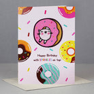 Birthday card with cat in donut and colorful sprinkles.